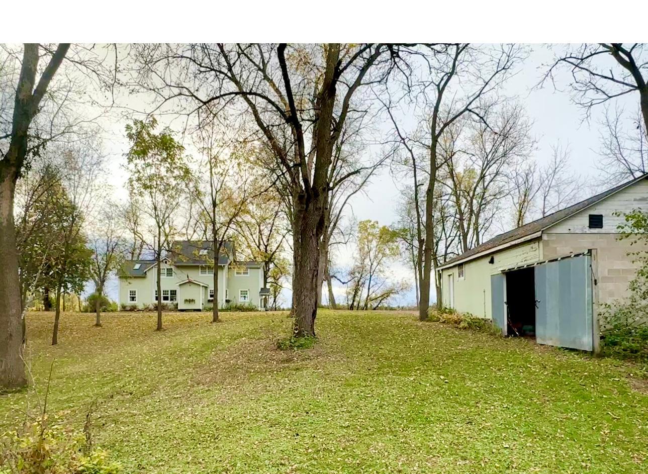A look back from the barn showing the side door to the back of the garage and the stately two story home of your dreams.