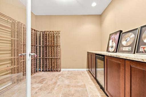 Lower-level wine room featuring cabinetry, generous countertop space, and room for all your favorite bottles.