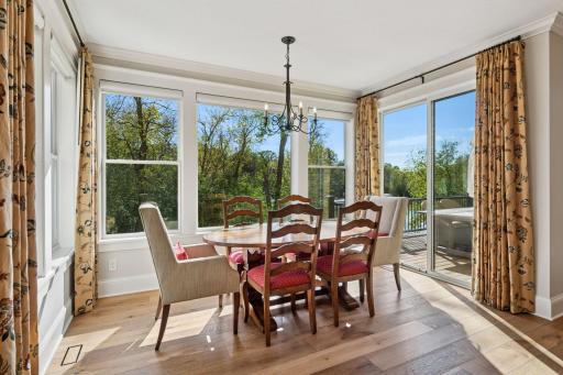 Dining area wrapped in windows overlooking pond and walks out to the deck.