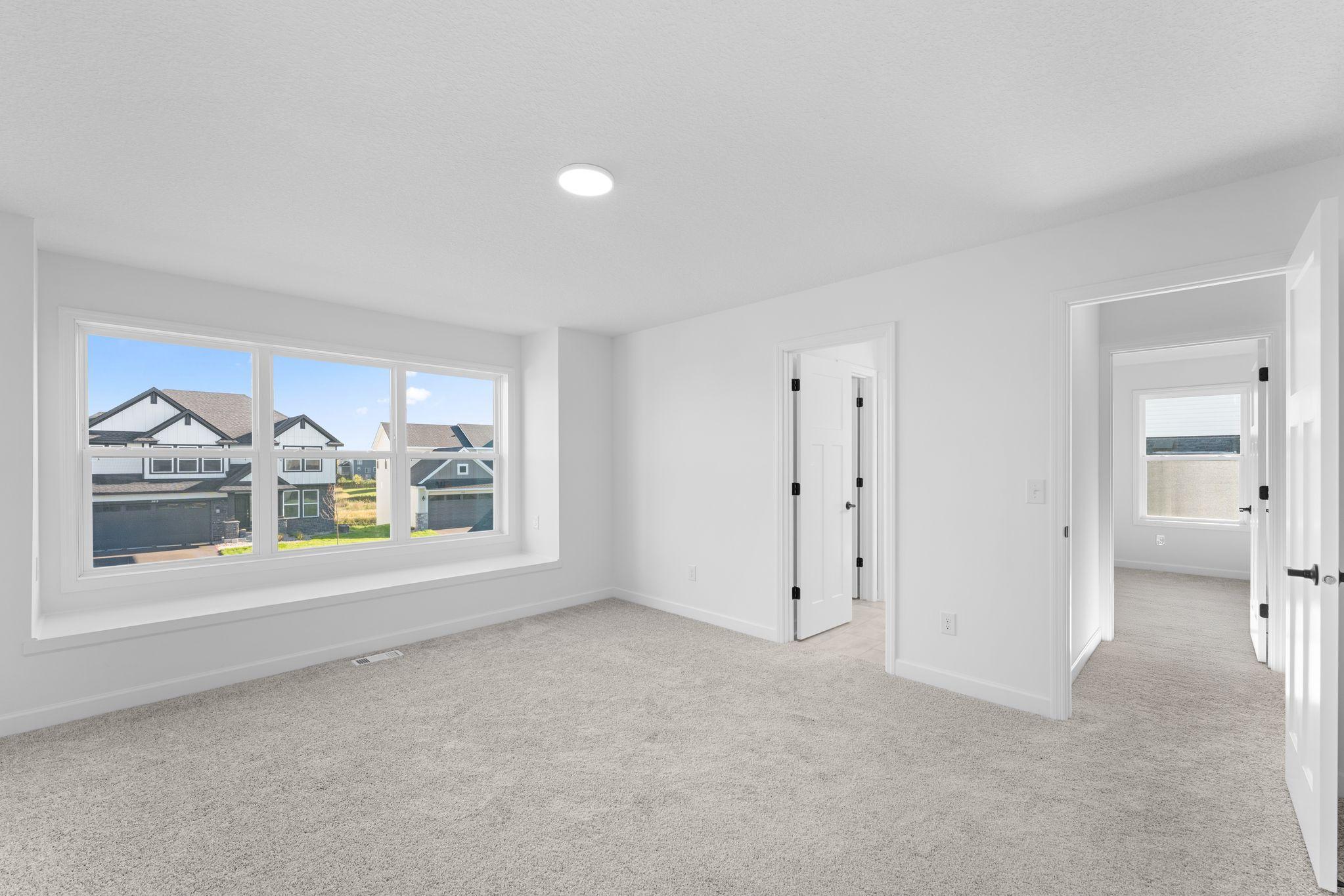 The primary bedroom embraces natural light streaming in from the large windows