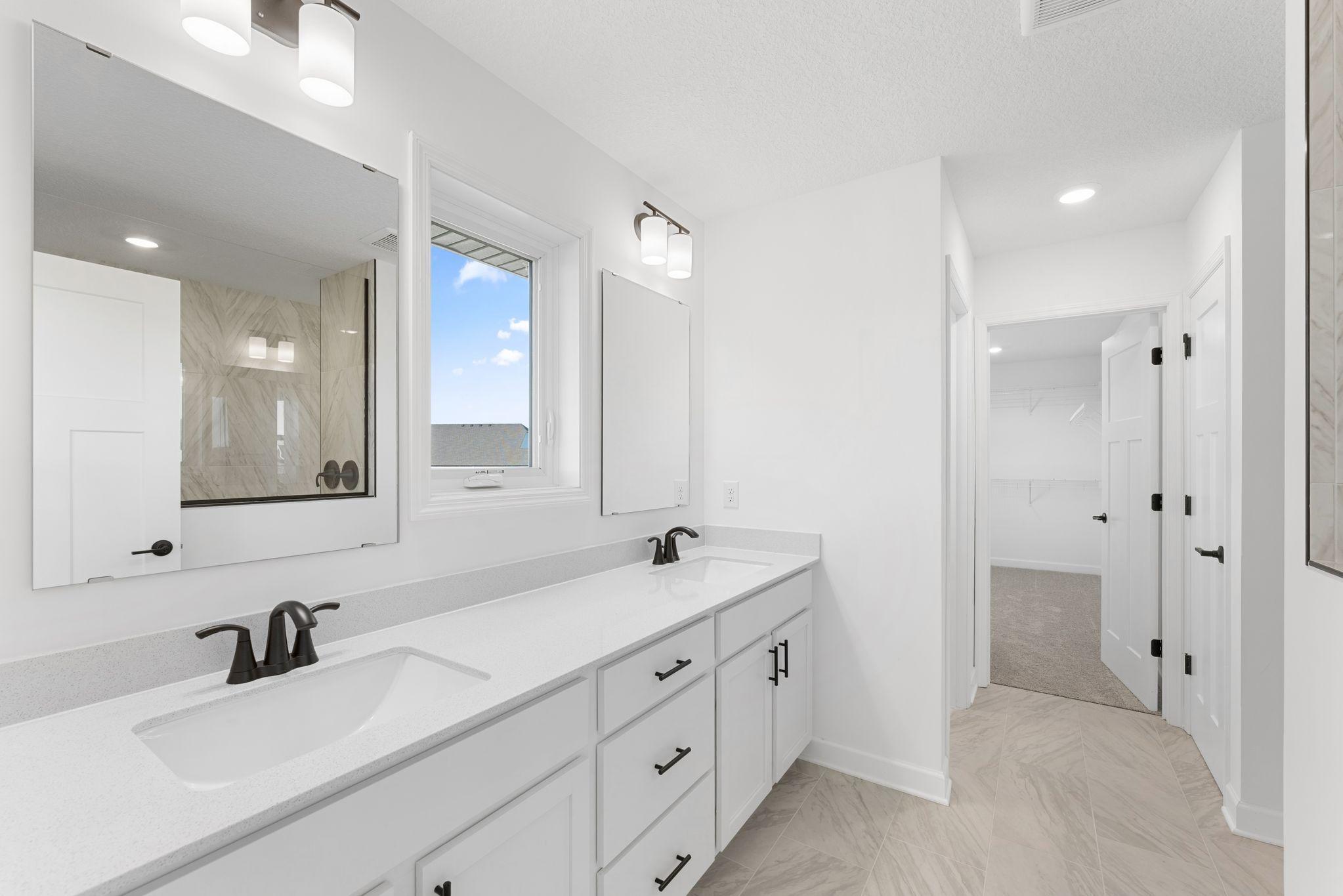 Dual rectangular undermount sinks and chrome fixtures sit atop the stylish vanity to complement busy lifestyles