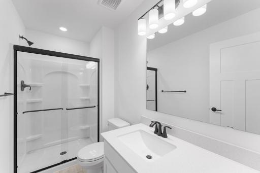 This bathroom is discreetly located down a hallway off the foyer, offering access to a single vanity and glass-enclosed shower.