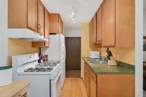 Another view of the kitchen showcasing plentiful cabinetry, updated appliances, and easy access to the dining area.