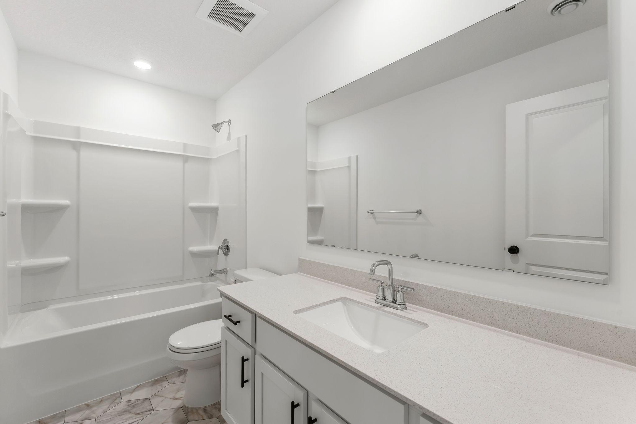 A full-sized bathroom on the second floor comes well-equipped with a generously sized quartz-topped vanity and a combination shower and tub to maximize the interior space.