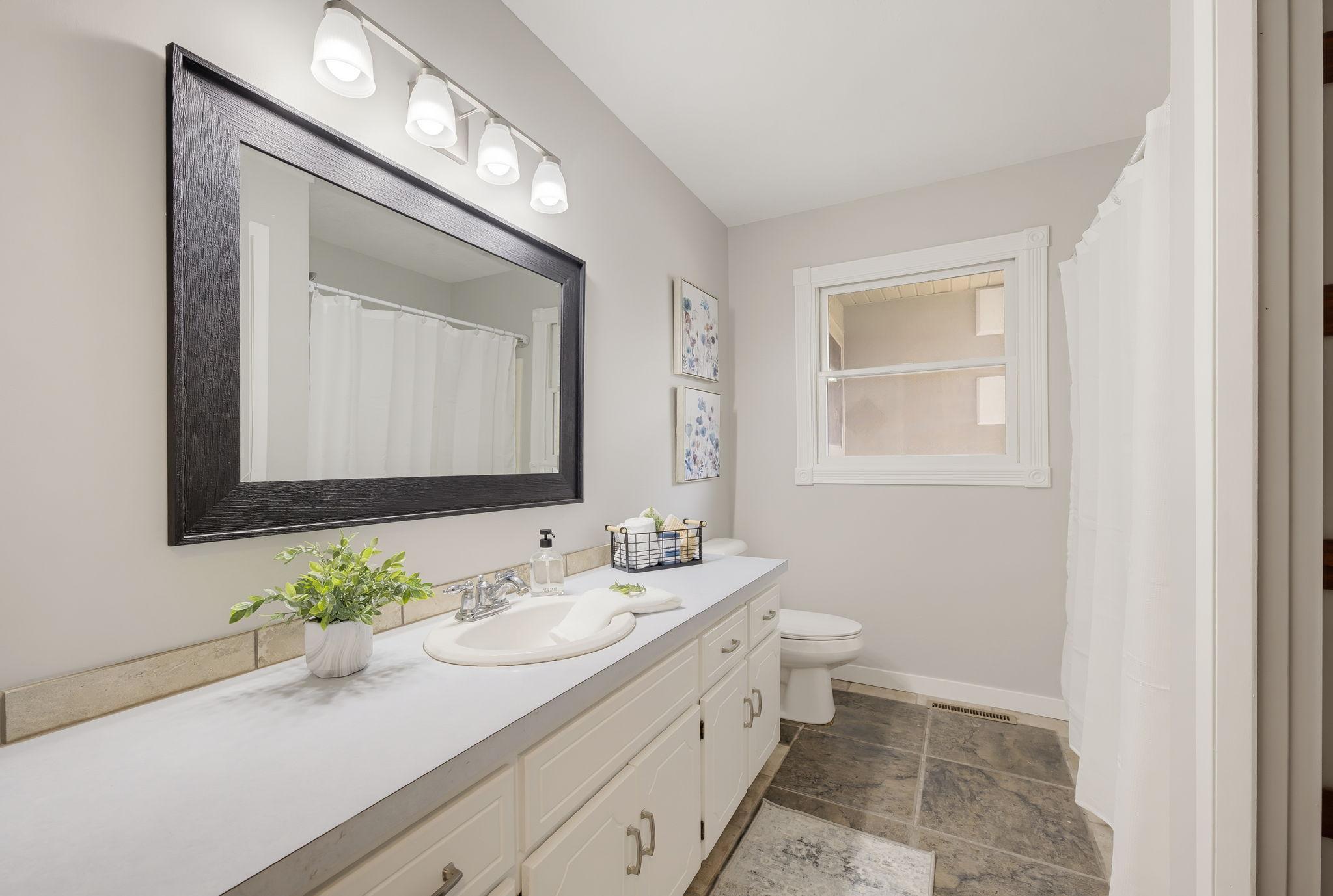 Main Level Bathroom with Tiled Floors, a Large Vanity, New Mirror & Lighting