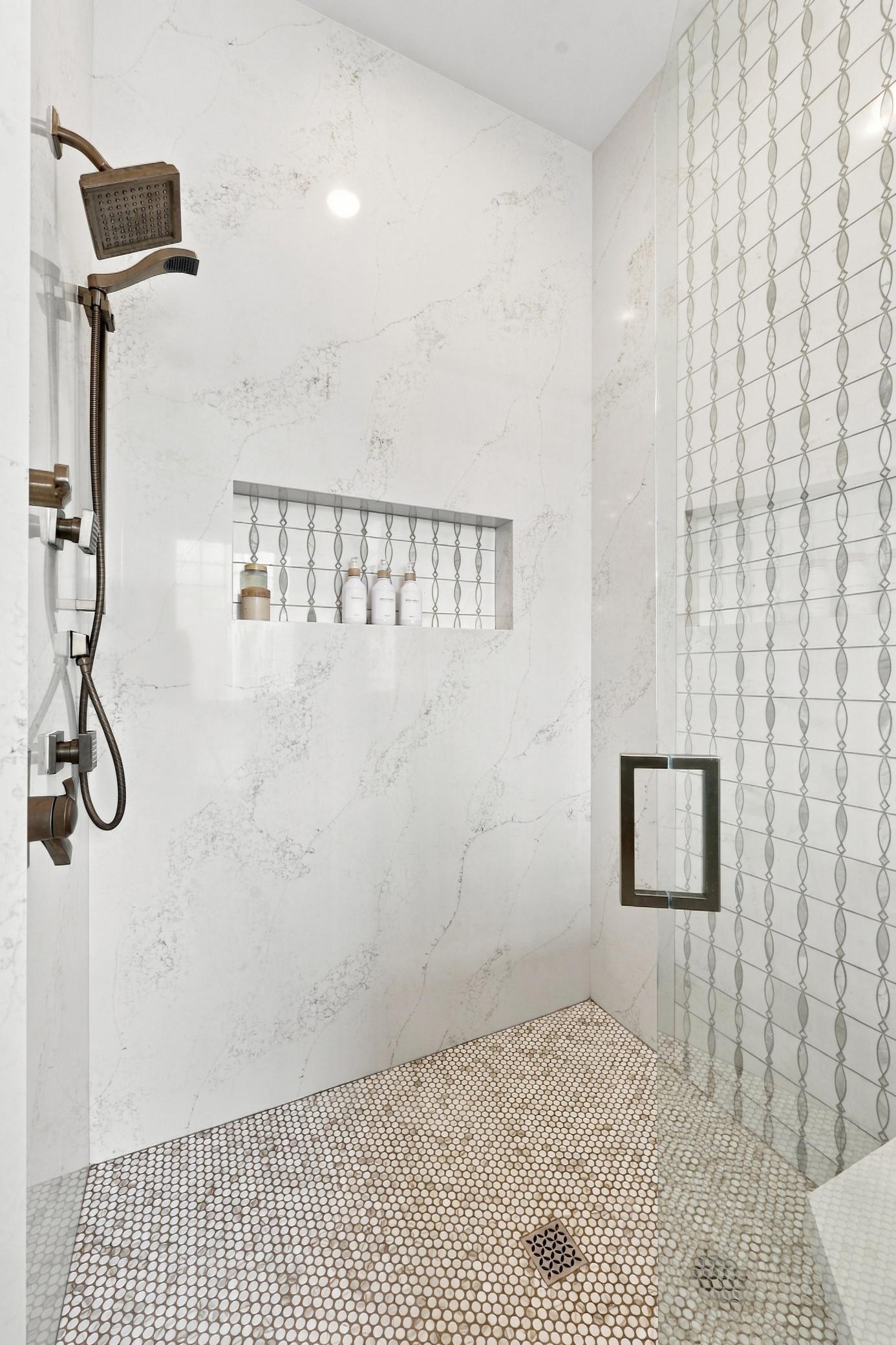 Custom tile shower with dual shower heads, niche for storage and bench seat