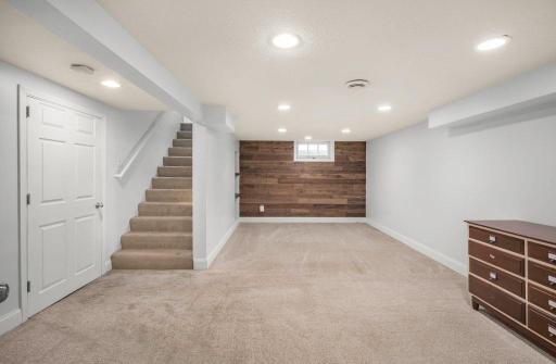 The finished basement adds even more room to spread outâperfect for a rec room, home gym, play space, or movie zone, with recessed lighting and a warm wood accent wall adding extra character.