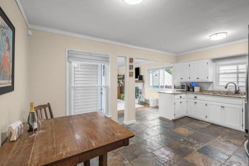 The heart of the home, this eat-in kitchen is made for morning coffee, shared meals, and lingering conversation, with white cabinetry, subway tile, and rich slate flooring adding warmth and character.