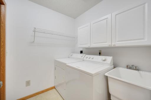 Laundry Day made easier! This dedicated laundry room offers convenient storage cabinets, shelving, and a utility sink to help keep everyday chores organized