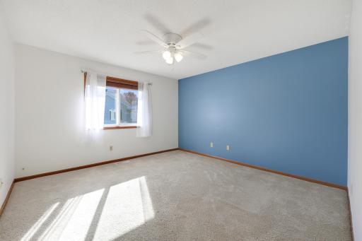 Afternoon sunlight fills the primary bedroom, creating a bright welcoming space, while the ceiling fan adds comfort throughout the seasons