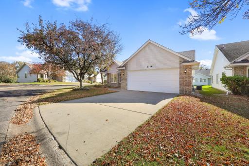 Situated on a corner lot along a gentle curve, this home features an attached two-car garage and a generous driveway for additional parking