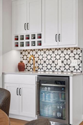 Conveniently located off the kitchen, this additional prep space features a sink, beverage refrigerator, and extra cabinetry for added storage.