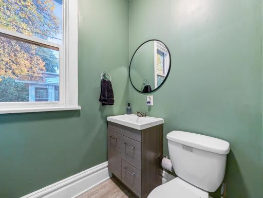 A fresh and cheerful bathroom with sage green walls, a modern vanity, and natural light from the window.