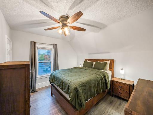 Comfortable bedroom featuring hardwood floors, a ceiling fan, and warm wood accents.