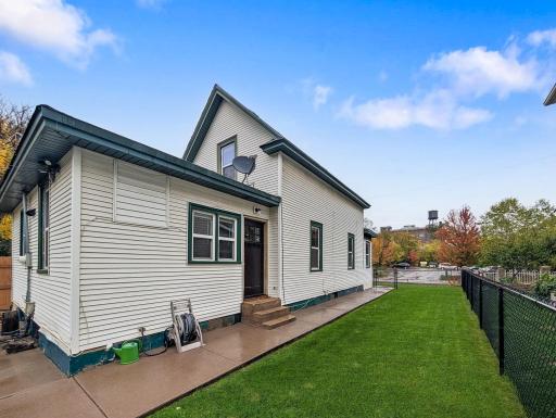 A side view of the home with a grassy yard and convenient access to the backyard.