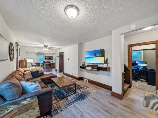 Spacious living room features an open layout, wood trim, and flooring that flows into the adjoining living area.