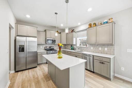 Fantastic quartz countertop island centers this tasteful kitchen