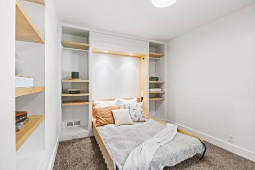 Bedroom two offers a full-size built-in Murphy bed with surrounding shelving, providing a versatile space for guests, an office, or everyday living.