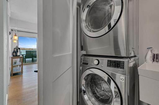 A convenient lower-level laundry closet features a full-size stacked washer and dryer, along with a utility sink, keeping everything organized and out of sight.