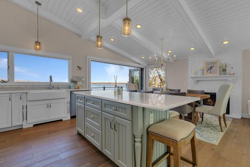 The open kitchen offers a large center island with seating, generous counter space, farmhouse-style sink, and abundant cabinetry, with easy access to the adjoining dining area.