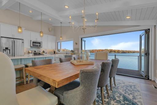 An impressive wall of folding glass doors with a retractable screen connects the dining area to the lakeside deck, offering unobstructed lake views and exceptional indoor-outdoor flow.