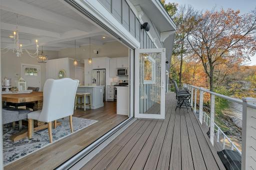The maintenance-free lakeside deck features cable railings that preserve the water views, with expansive folding glass doors and a retractable screen connecting directly to the dining area.