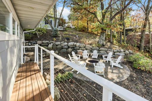 Beautifully landscaped grounds feature extensive natural stone retaining walls, terraced walkways, and a separate lakeside firepit patio.