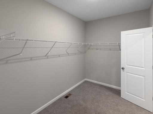 PHOTO OF A DIFFERENT HOME WITH SIMILAR PLAN. FINISHES MAY VARY. Spacious Primary Suite Walk-in Closet.