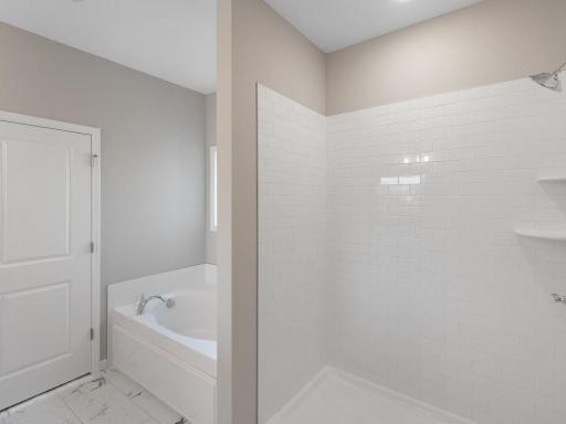 PHOTO OF A DIFFERENT HOME WITH SIMILAR PLAN. FINISHES MAY VARY. Primary Bath features a Soaking Tub and Separate Shower with Tile Wall Surround.