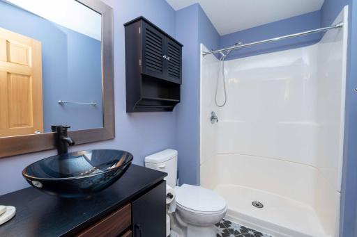 Lower-level bathroom with a vessel sink and walk-in shower.