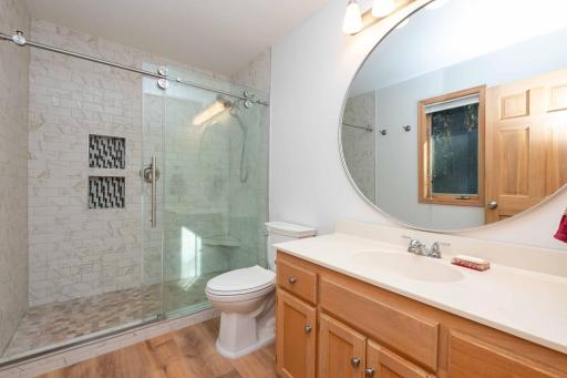 Featuring a tiled shower, glass doors, and a generous vanity.