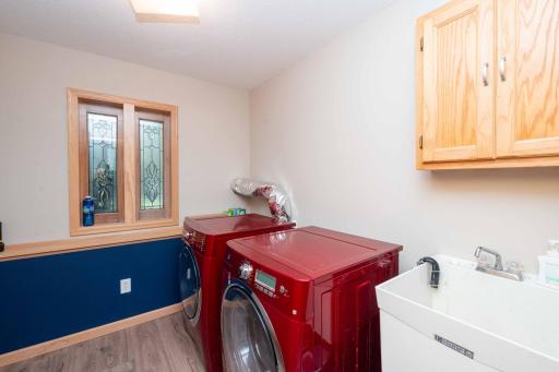 Laundry room with a utility sink, cabinetry, and a window.